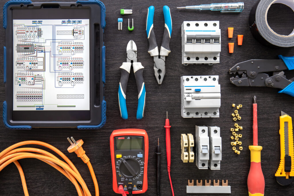 different electrical tools on wooden background, flat lay.