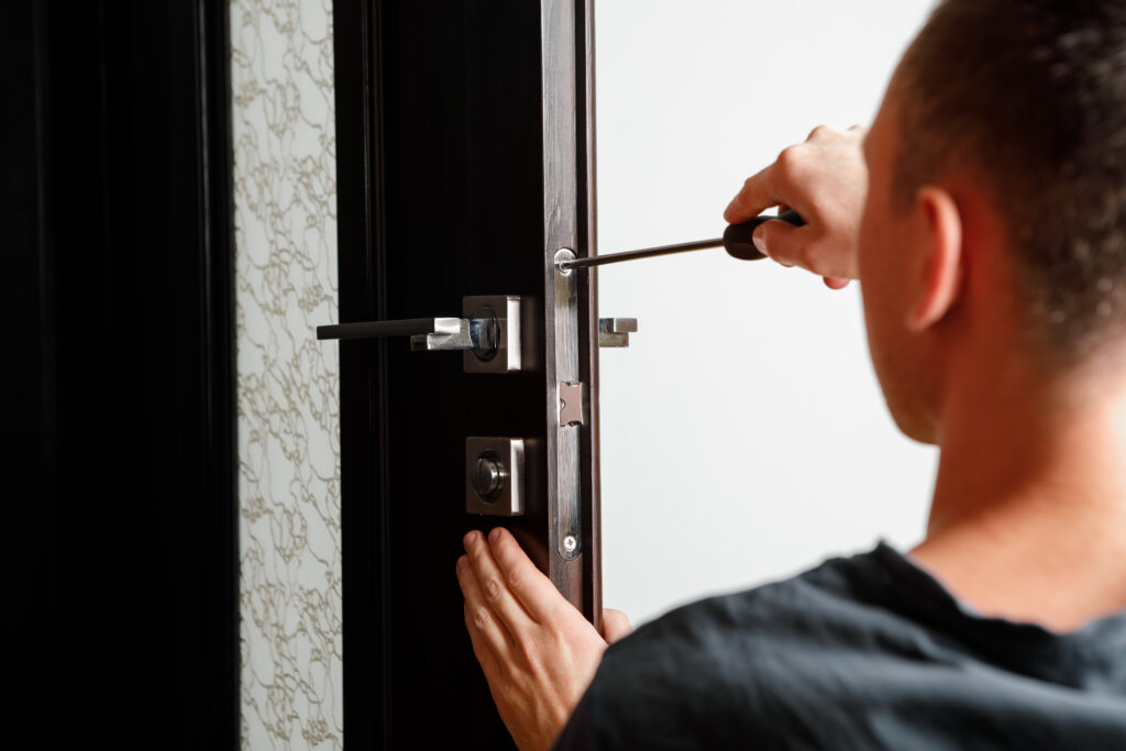 man repairing the doorknob. carpenter working on lock installati