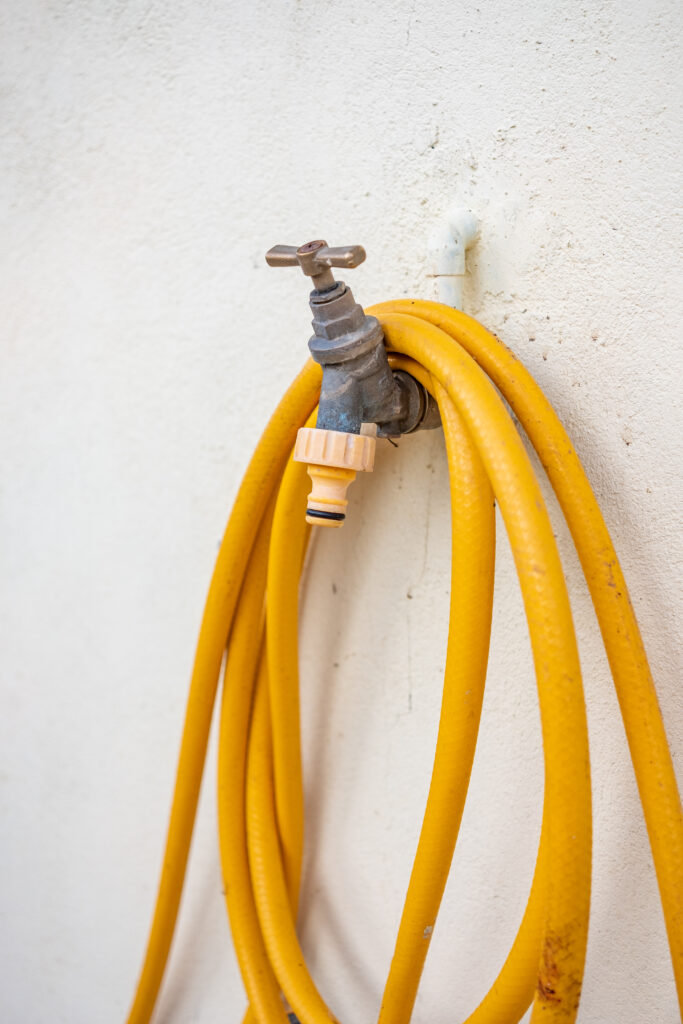 outdoor tap and garden hose suspended on an exterior wall